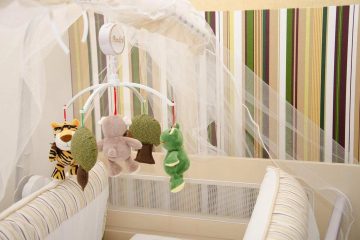 Berceau avec jouets suspendus et moustiquaire dans une chambre d'enfant