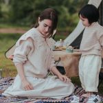 Deux enfants jouent sur un tapis à proximité d'une tente de camping beige en plein air